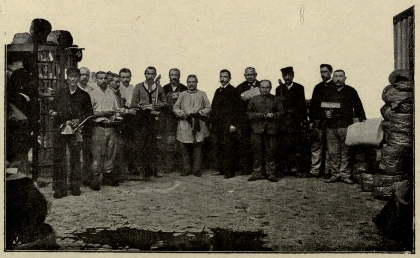 Gruppenfoto: Etwa fünfzehn Arbeiter des Fabrikrats stehen in einem Hof der Fabrik, jeder hält ein Werkzeug oder ein Erzeugnis seines Handwerks.