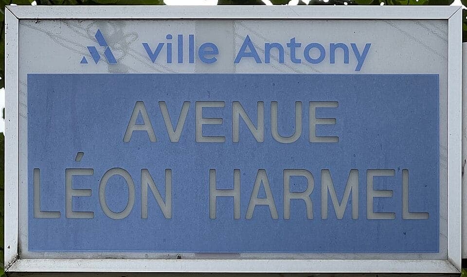 Blue street sign: “Avenue Léon Harmel”, with the logo of the town of Antony.