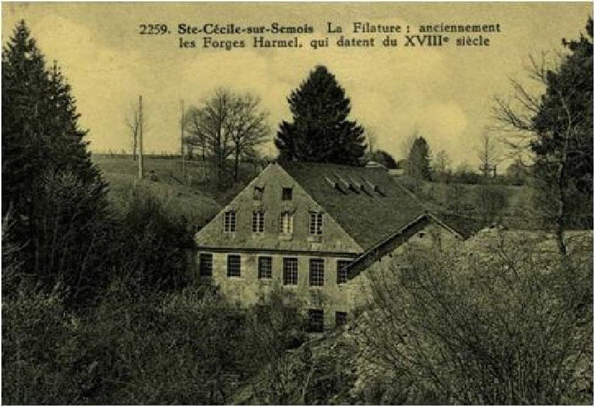 In the hollow of the Semois valley, the stone building of the spinning mill, three levels high with dormers in its roof, among fir trees.