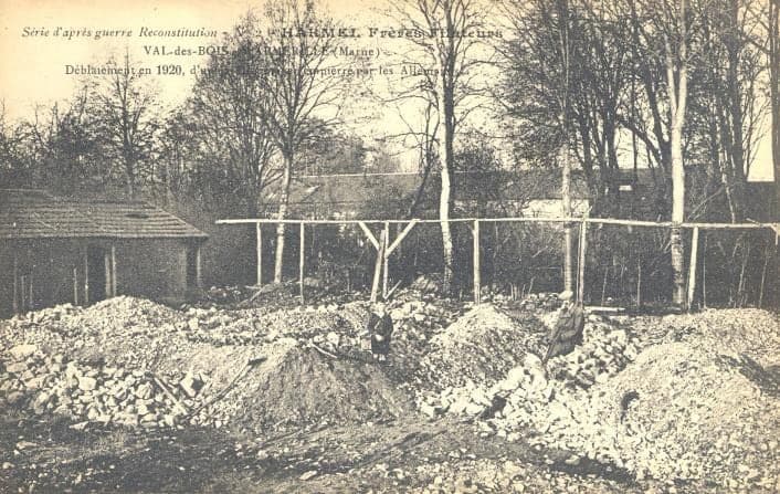 Heaps of rubble lined up before the mill's trees during the clearing of the destroyed buildings; a temporary shed on the left.