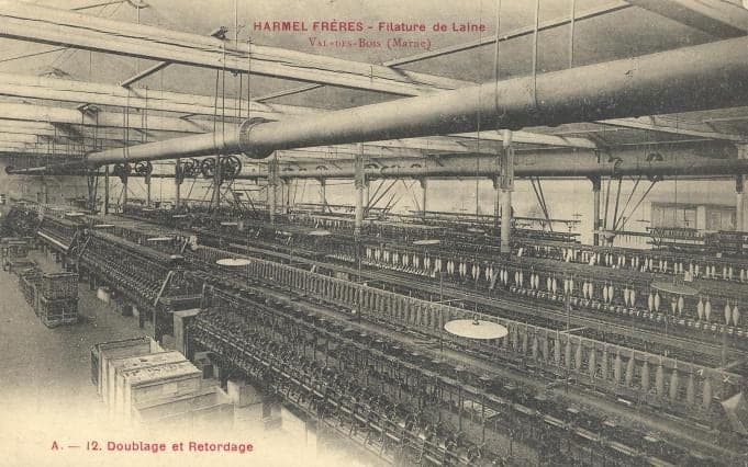 The doubling and twisting room: long rows of machines loaded with bobbins beneath the line shafts and a large duct.