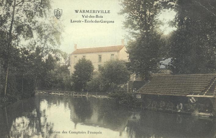 Tinted card: the tree-lined Suippe, the wash-house roof on the right and, in the background, the boys' school building.