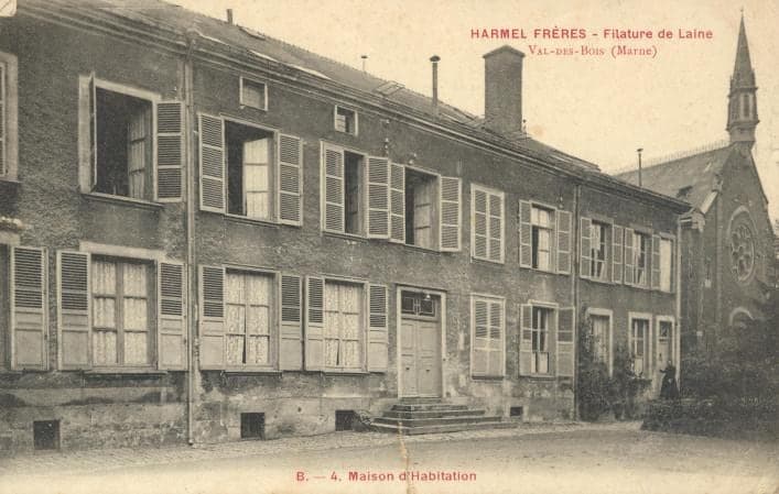 A long shuttered house on a paved courtyard, with front steps; the bell tower of the Val-des-Bois chapel appears on the right.