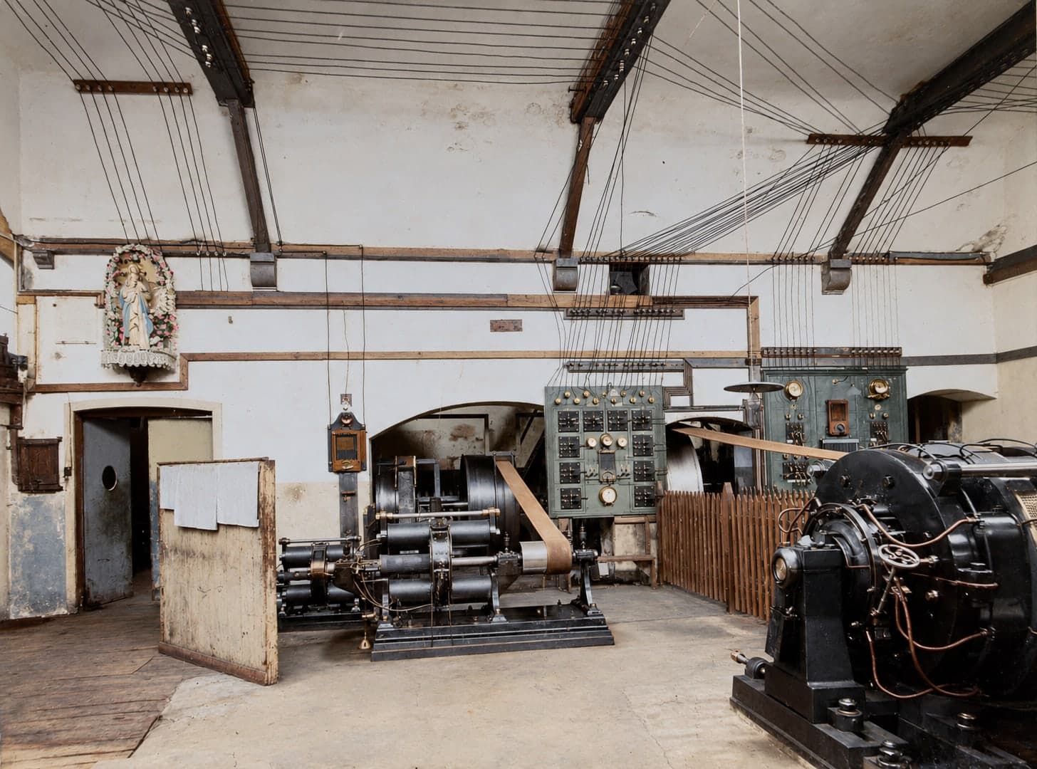 Engine room with dynamos and an electrical switchboard; in a niche in the wall, on the left, a statue of the Virgin.