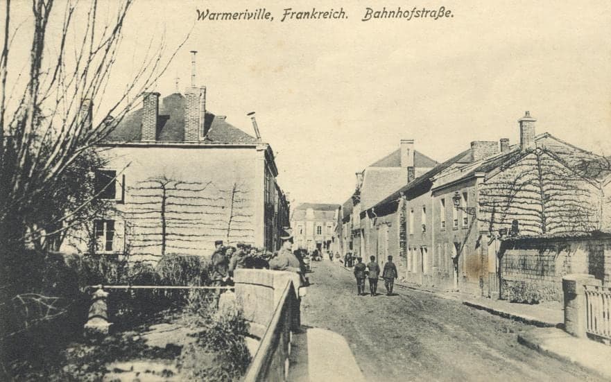 Station Street in Warmeriville under German occupation: houses with espaliers, a bridge over the Suippe and a few soldiers on the road.