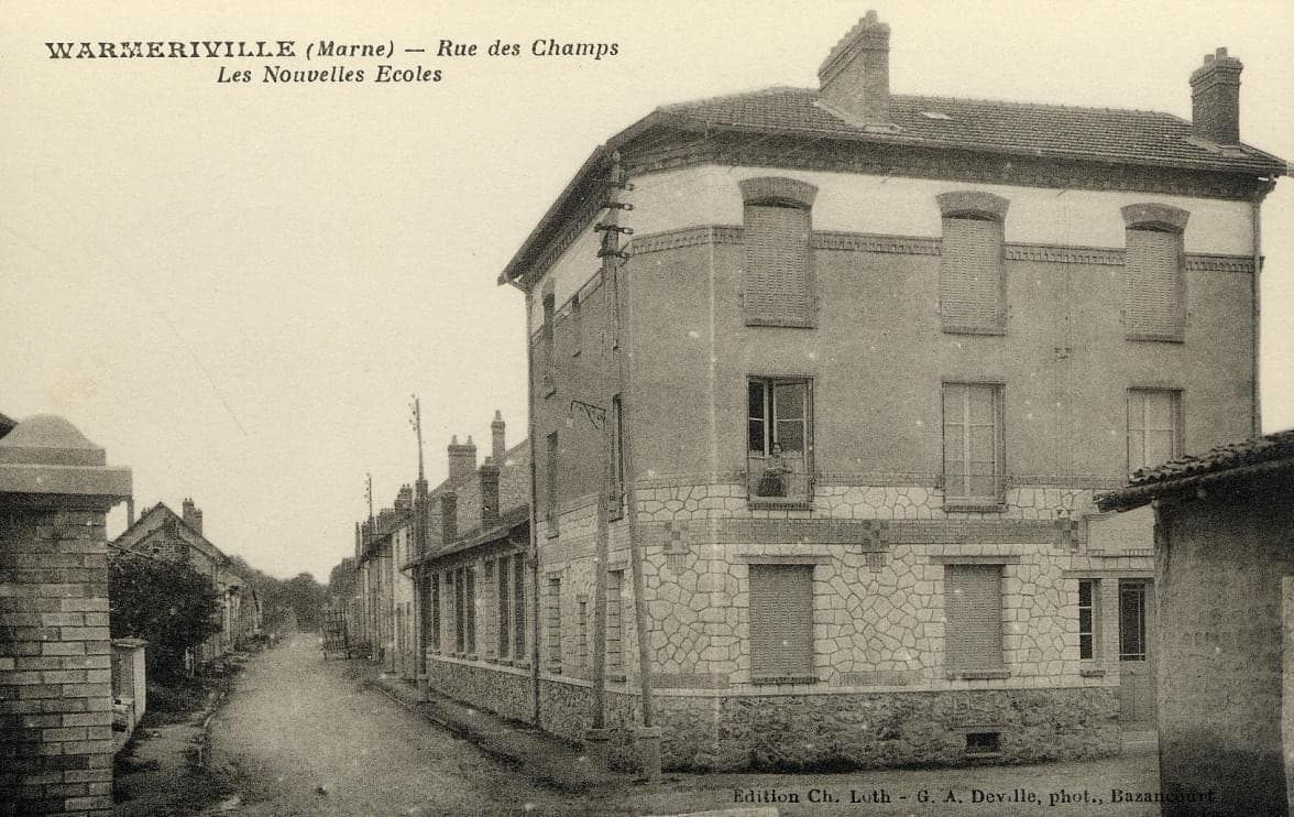 The two-storey building of the new schools, at the corner of the Rue des Champs, lined with low houses.
