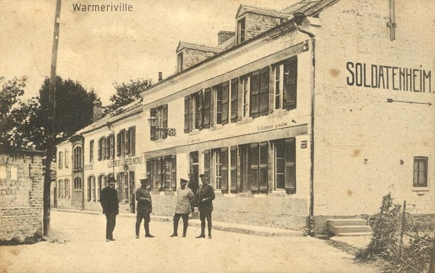 A Warmeriville street during the occupation: on the gable of a house, the inscription “Soldatenheim”; four German soldiers pose in front.